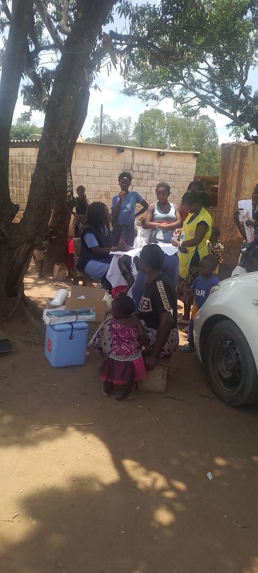 Children and adults gathered under a tree for community programming